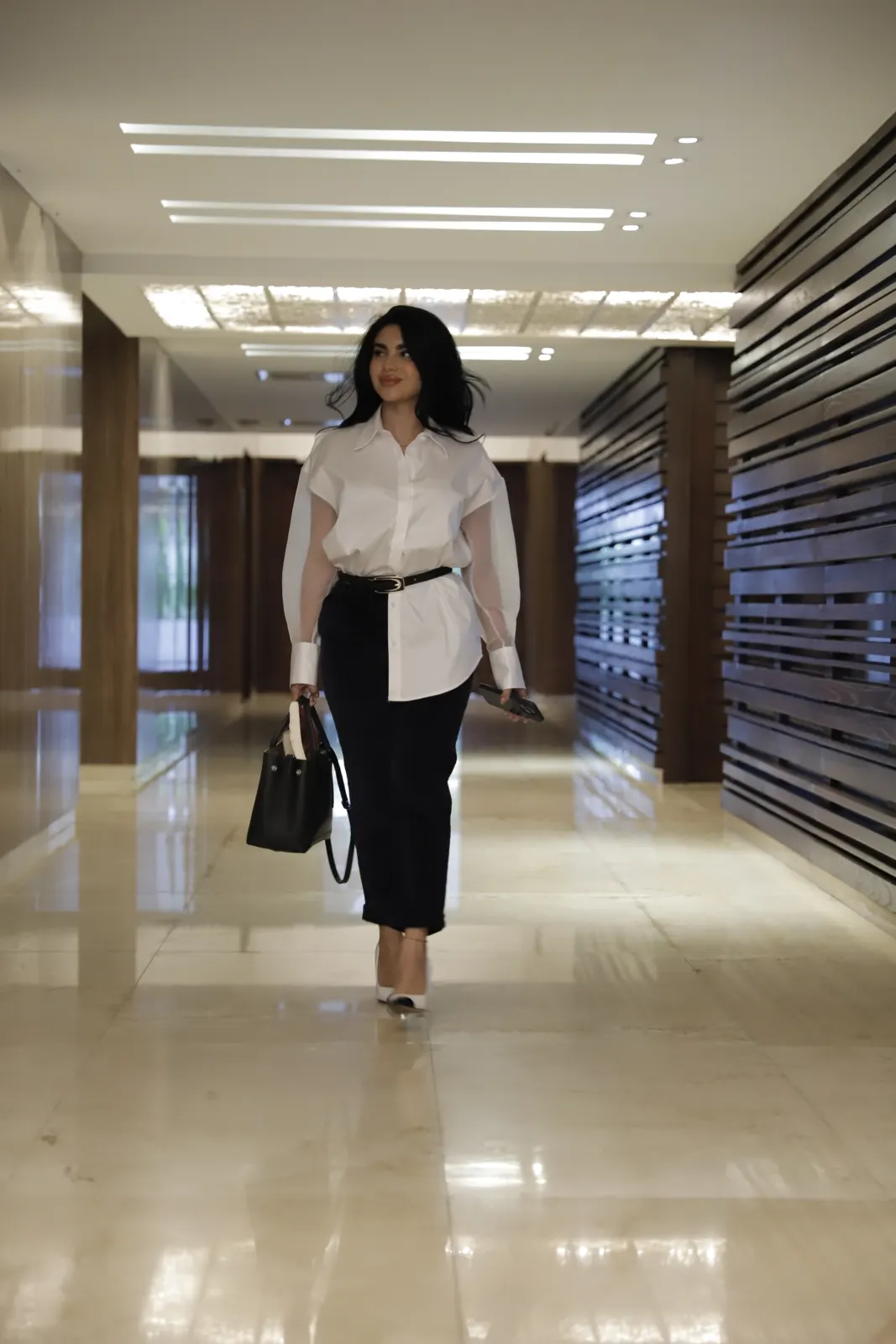 Melba camina segura por un pasillo de oficina